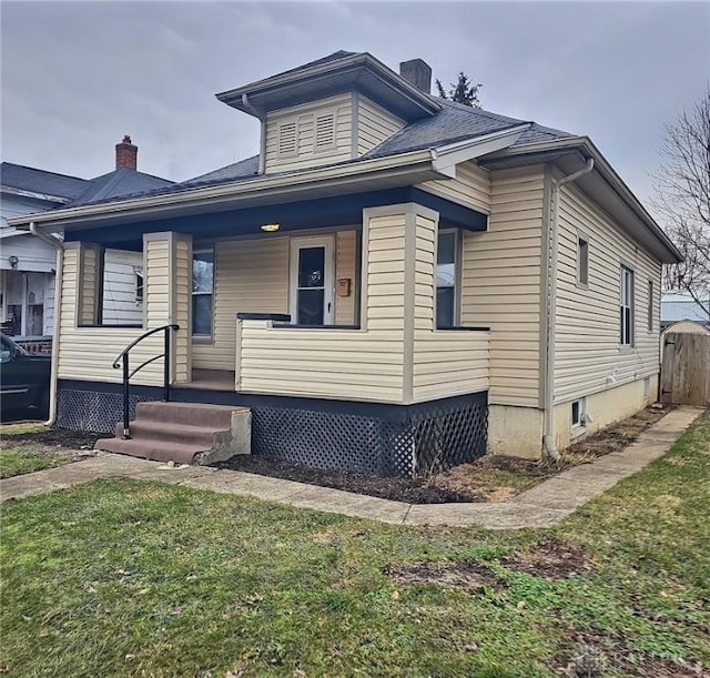 bungalow featuring covered porch, a shingled roof, and a chimney