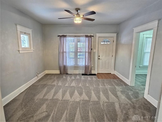 carpeted foyer featuring plenty of natural light, baseboards, and ceiling fan