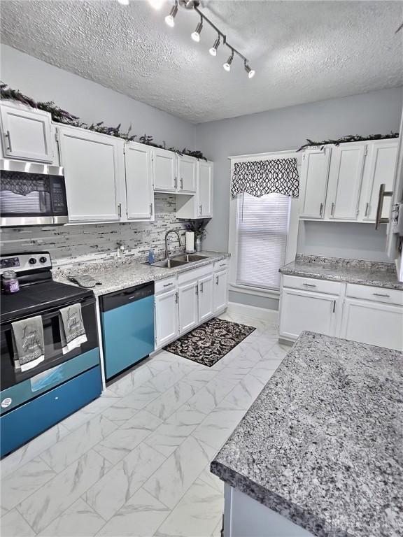 kitchen featuring marble finish floor, stainless steel appliances, a textured ceiling, white cabinetry, and a sink