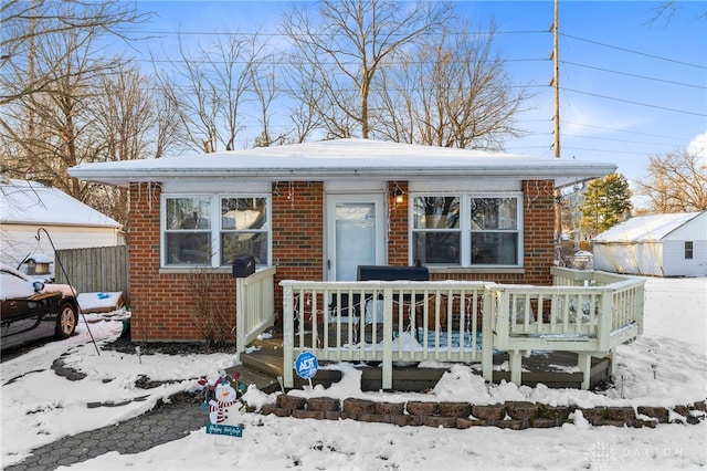 bungalow featuring fence, a deck, and brick siding