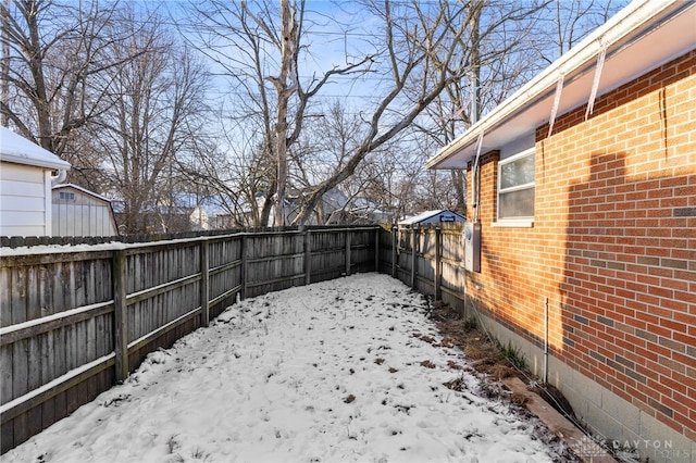 snowy yard featuring a fenced backyard