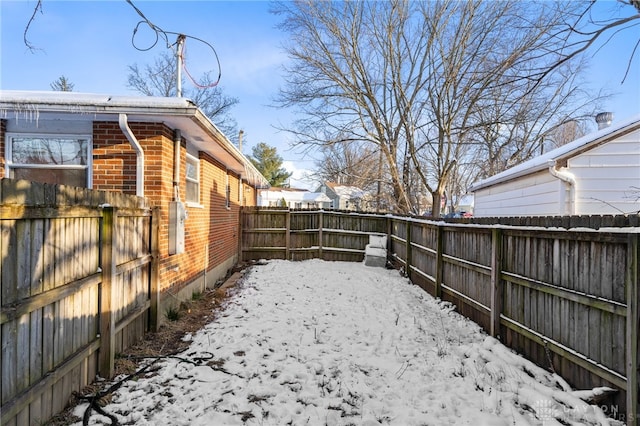 yard layered in snow with a fenced backyard