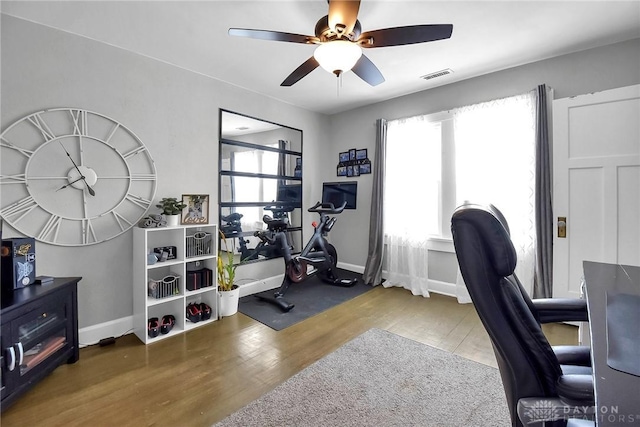 office featuring dark wood-type flooring, visible vents, baseboards, and a ceiling fan