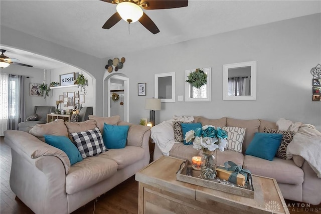 living room with ceiling fan, arched walkways, and dark wood-style flooring