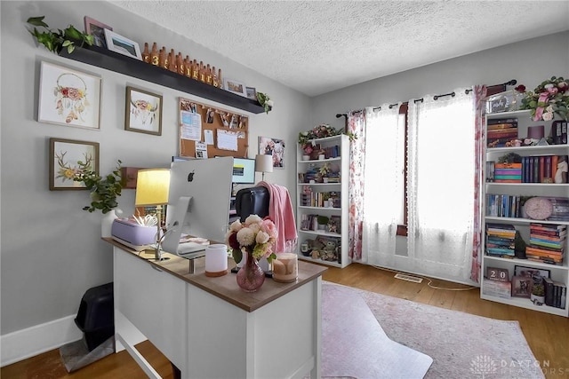 office space with a textured ceiling, baseboards, and wood finished floors