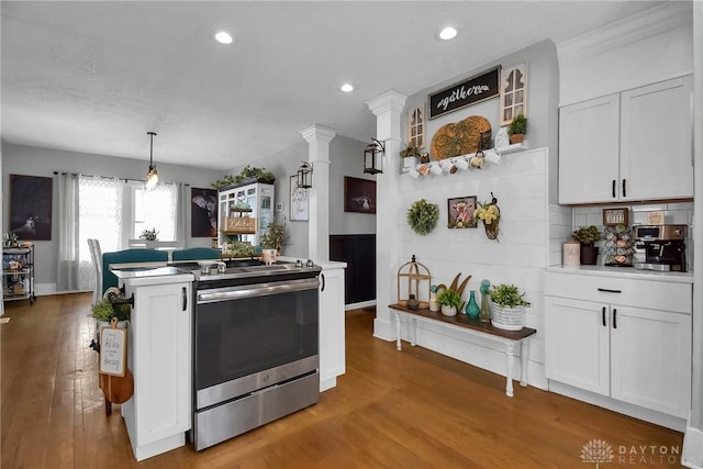 kitchen featuring light wood-type flooring, stainless steel electric range, decorative backsplash, and white cabinets