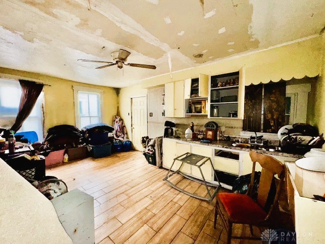 kitchen featuring ceiling fan, a sink, white cabinetry, and light wood-style floors