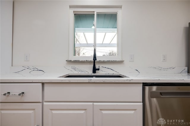 kitchen with dishwasher, light stone counters, a sink, and white cabinets