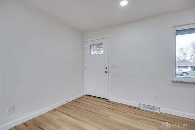 foyer with light wood-style floors, baseboards, and visible vents