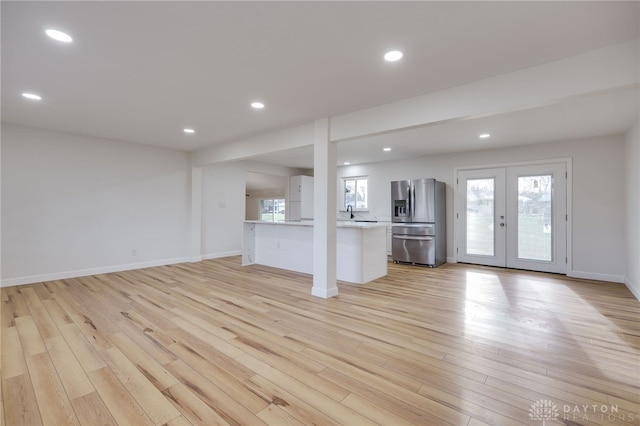 unfurnished living room with light wood finished floors, recessed lighting, baseboards, and french doors