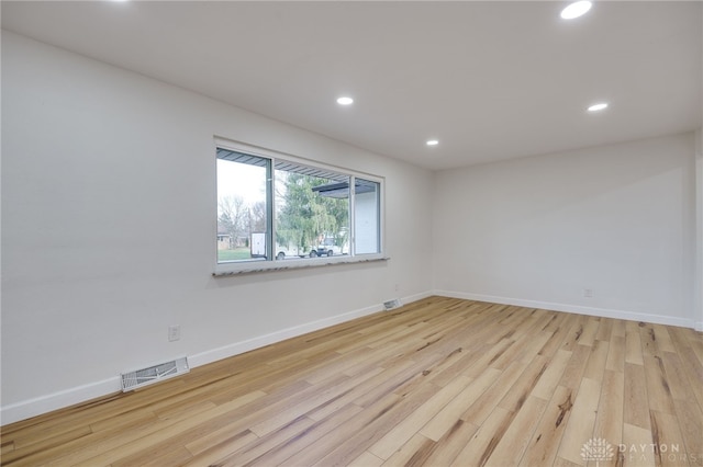 unfurnished room with light wood-type flooring, baseboards, visible vents, and recessed lighting