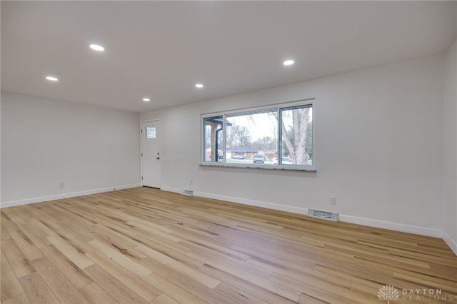 empty room with baseboards, light wood-type flooring, visible vents, and recessed lighting