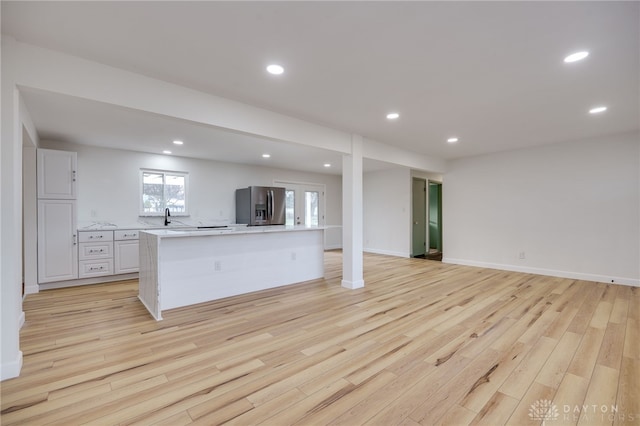 kitchen featuring white cabinets, open floor plan, a center island, light countertops, and stainless steel refrigerator with ice dispenser