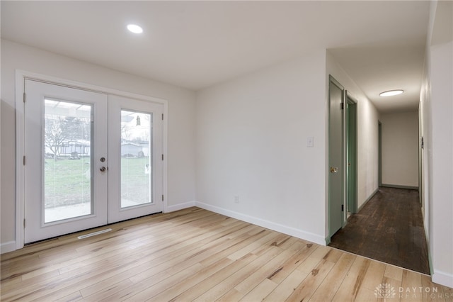 empty room with baseboards, wood finished floors, and french doors