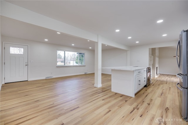 kitchen featuring light wood finished floors, white cabinetry, appliances with stainless steel finishes, and light stone counters