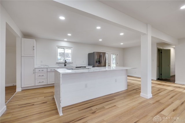 kitchen featuring a large island, white cabinetry, a sink, and stainless steel fridge with ice dispenser