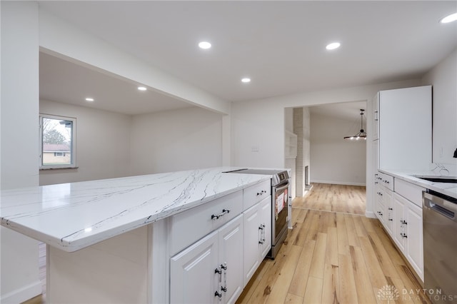 kitchen with light stone counters, appliances with stainless steel finishes, white cabinetry, and recessed lighting