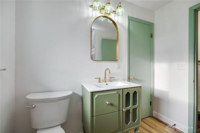 bathroom with toilet, baseboards, wood finished floors, and vanity