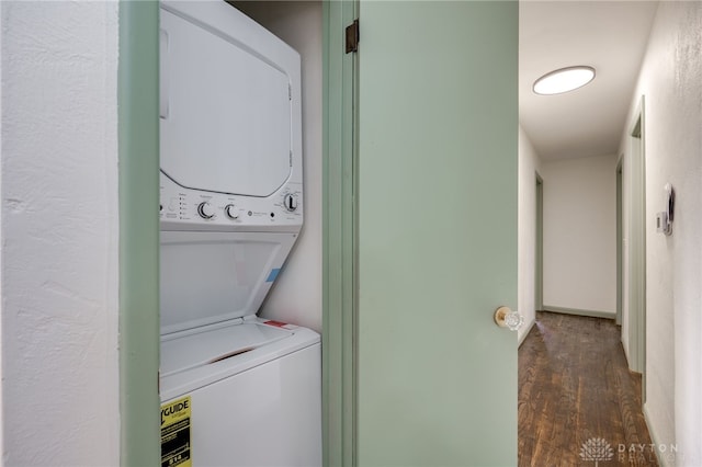 washroom featuring stacked washer and dryer, laundry area, and dark wood-type flooring