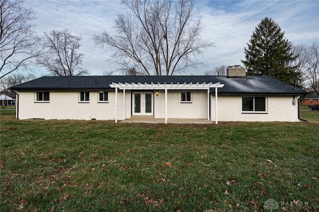 rear view of house featuring a patio, a chimney, a lawn, and french doors