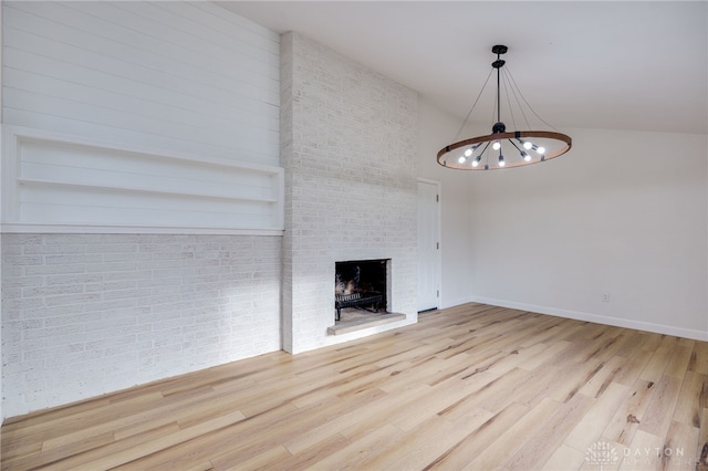 unfurnished living room with a chandelier, built in shelves, baseboards, light wood-style floors, and a brick fireplace