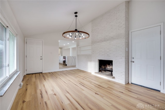 unfurnished living room featuring high vaulted ceiling, a brick fireplace, light wood-style flooring, and baseboards