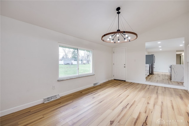 spare room with lofted ceiling, light wood finished floors, visible vents, and baseboards