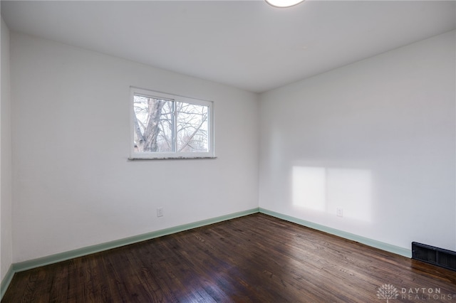 spare room featuring baseboards, visible vents, and dark wood-style flooring