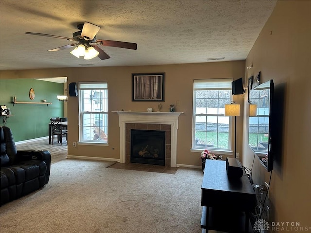 living room with a textured ceiling, a fireplace, visible vents, and light colored carpet