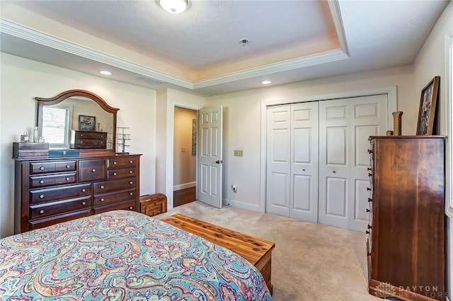 bedroom with baseboards, a raised ceiling, a closet, and light colored carpet