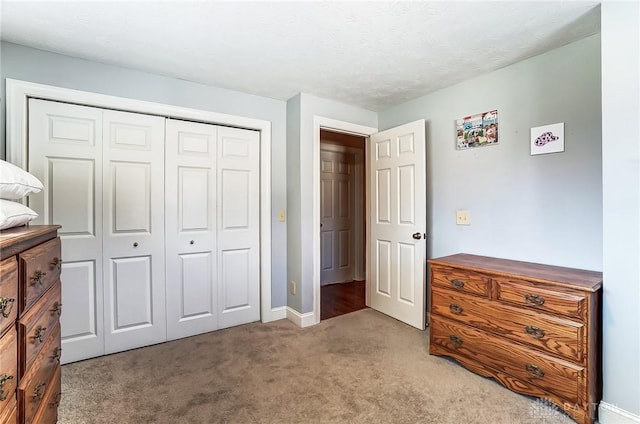 bedroom featuring light carpet, a textured ceiling, baseboards, and a closet