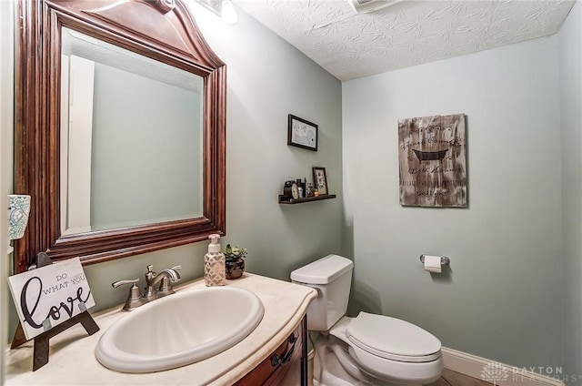 half bathroom with a textured ceiling, toilet, and vanity