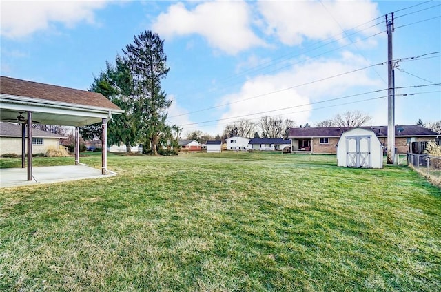 view of yard featuring an outbuilding, a patio, a shed, and fence