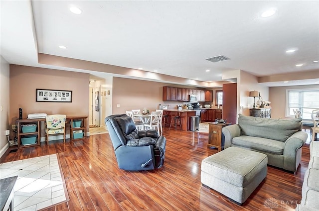 living area featuring baseboards, visible vents, wood finished floors, and recessed lighting