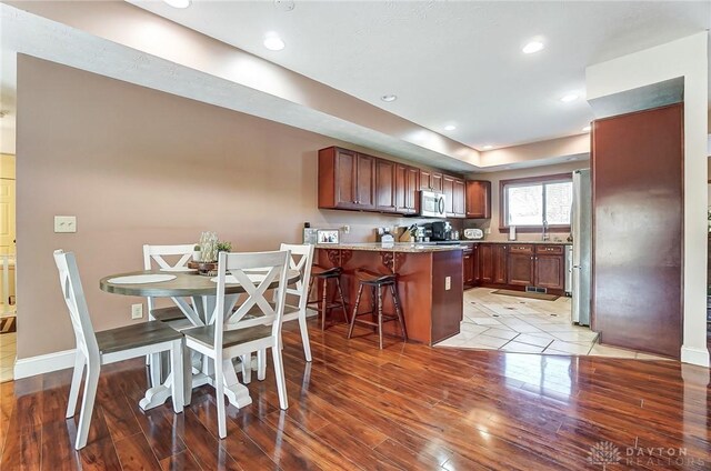 kitchen featuring a peninsula, light wood finished floors, appliances with stainless steel finishes, and a breakfast bar