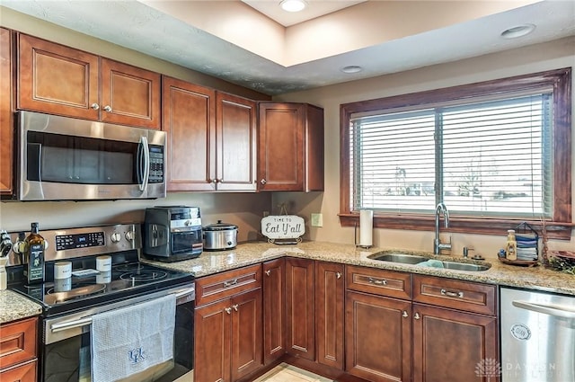 kitchen featuring stainless steel appliances, recessed lighting, a sink, and light stone countertops