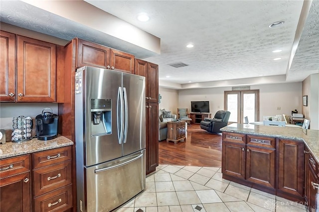 kitchen featuring recessed lighting, visible vents, stainless steel fridge with ice dispenser, open floor plan, and light stone countertops