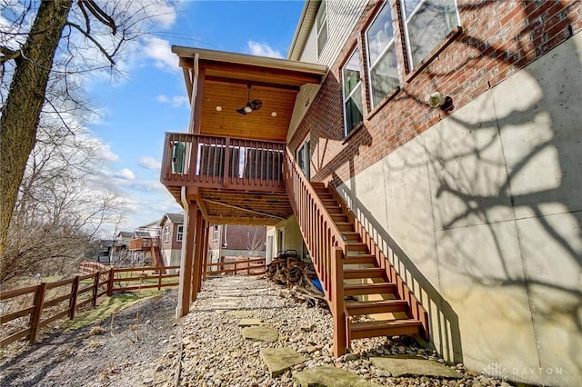 back of house with brick siding, fence, and stairs