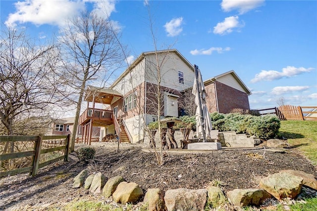 back of property with stairs, brick siding, and fence