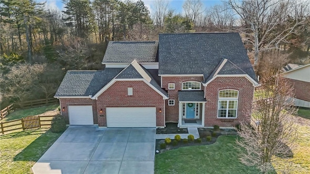 traditional-style house featuring a front yard, an attached garage, fence, and brick siding