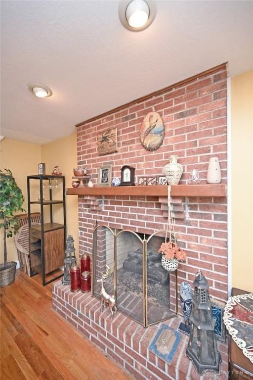 living area with a brick fireplace and wood finished floors