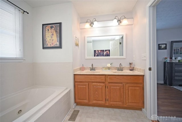 full bath featuring double vanity, a garden tub, and a sink