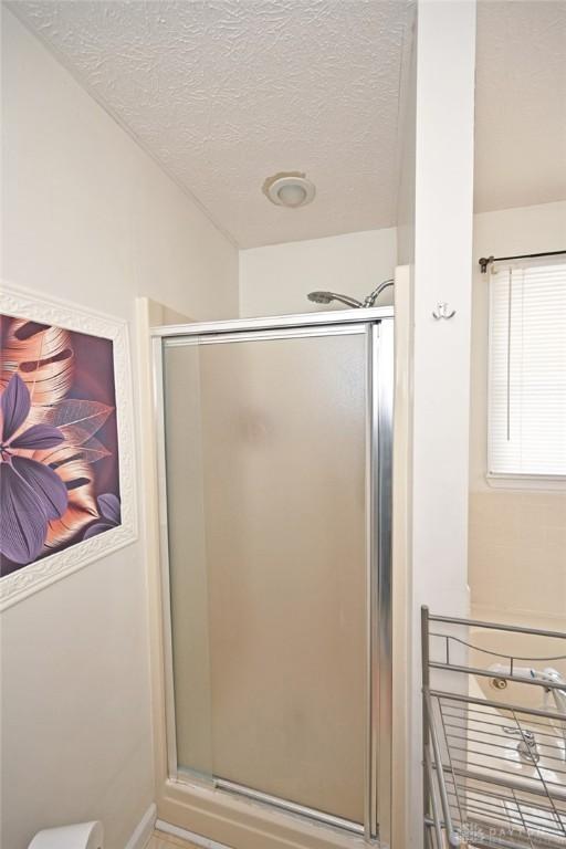 bathroom featuring a textured ceiling and a stall shower