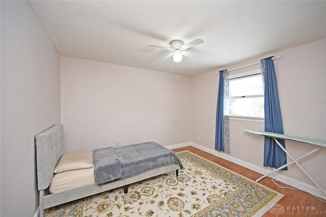 bedroom with a ceiling fan, baseboards, and wood finished floors