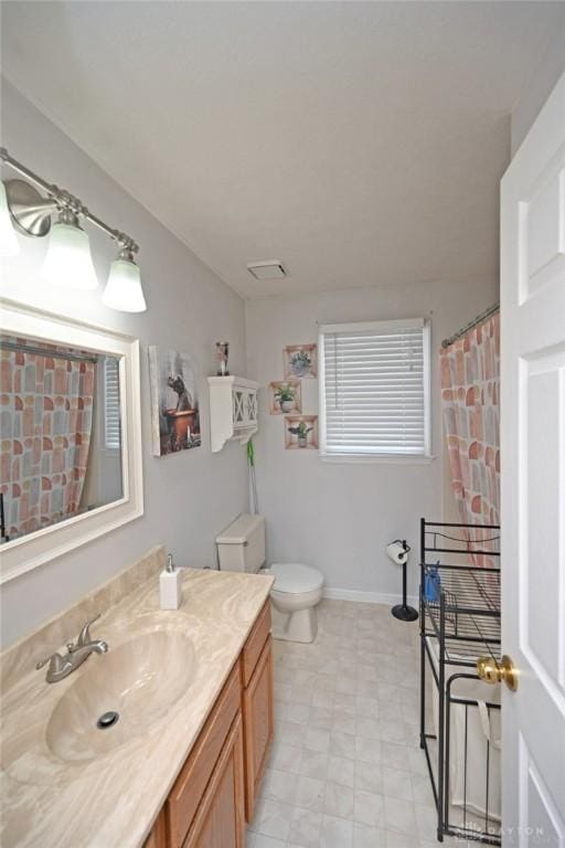 bathroom featuring baseboards, vanity, and toilet