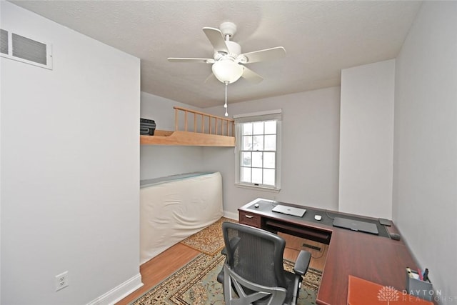 office space featuring ceiling fan, wood finished floors, visible vents, and baseboards