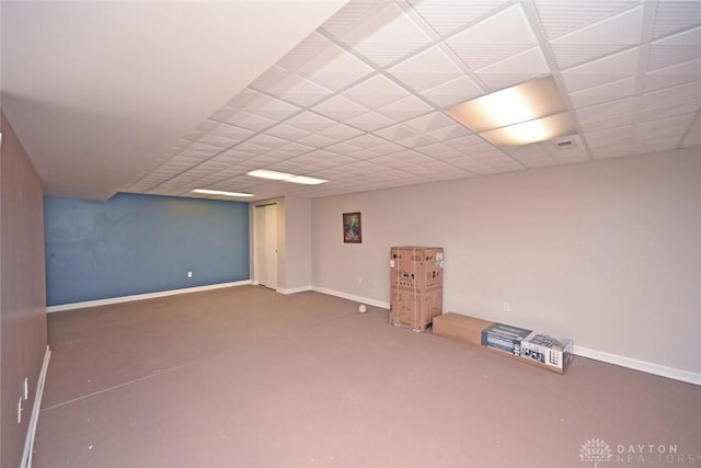 finished below grade area with visible vents, a paneled ceiling, and baseboards