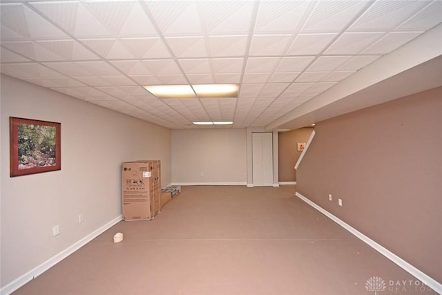 finished below grade area featuring a paneled ceiling and baseboards