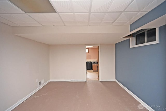 finished below grade area with a paneled ceiling, baseboards, and visible vents