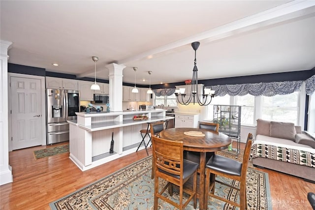 dining space with light wood-style floors, recessed lighting, a notable chandelier, and ornate columns